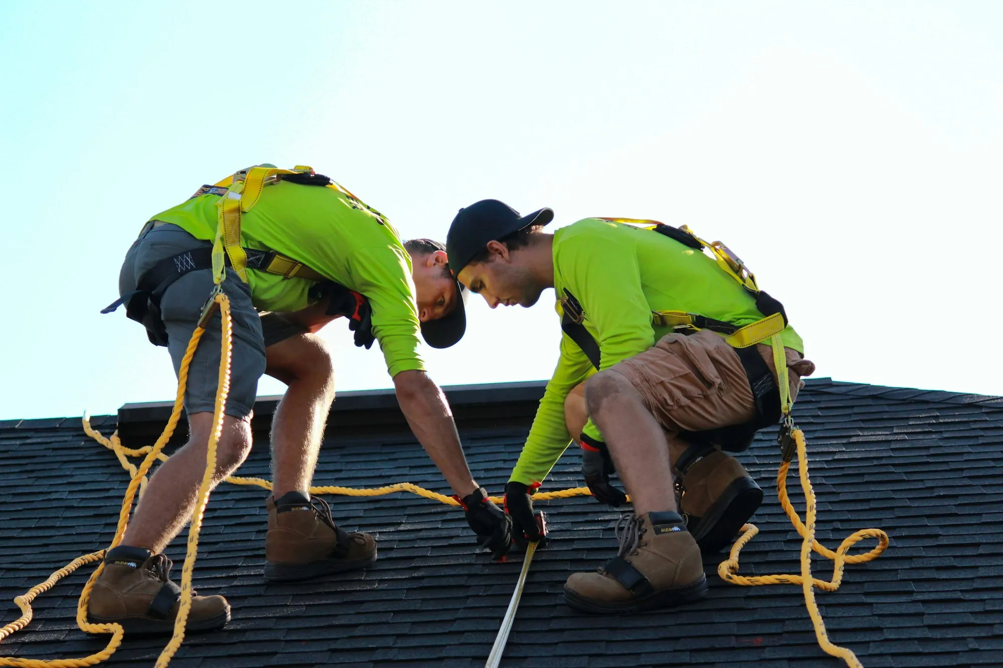 Two roofers working across a residential shingle roof