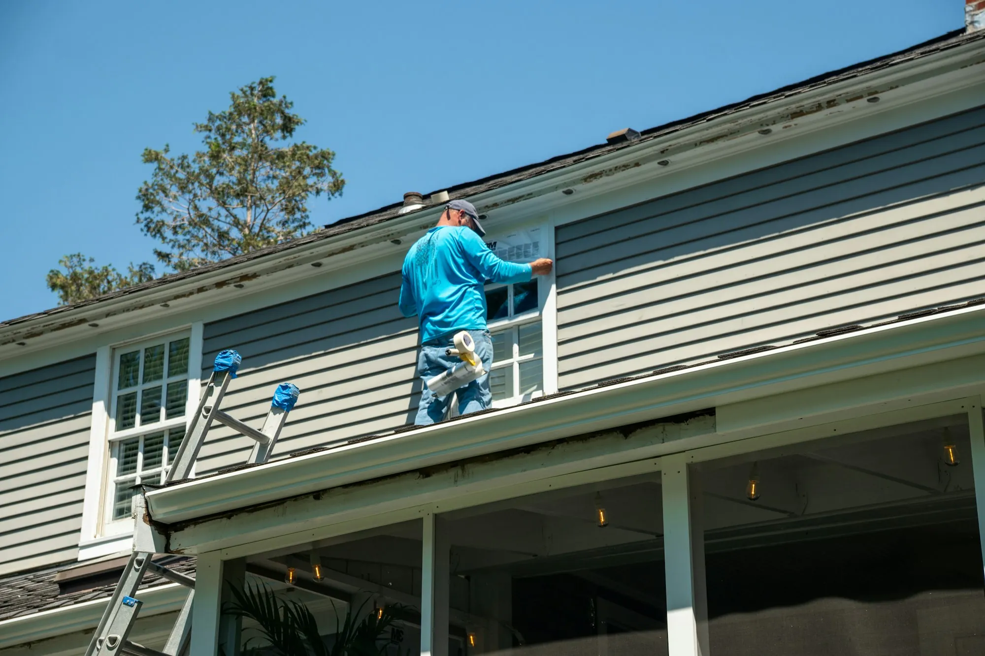 Contractor on a ladder working on siding and window trim