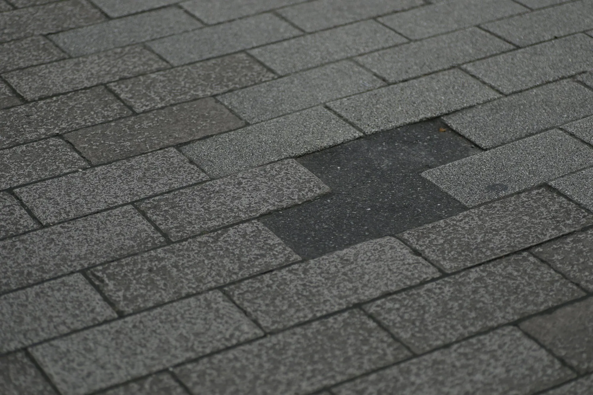 Storm-damaged asphalt shingle roof with shingles missing from the slope